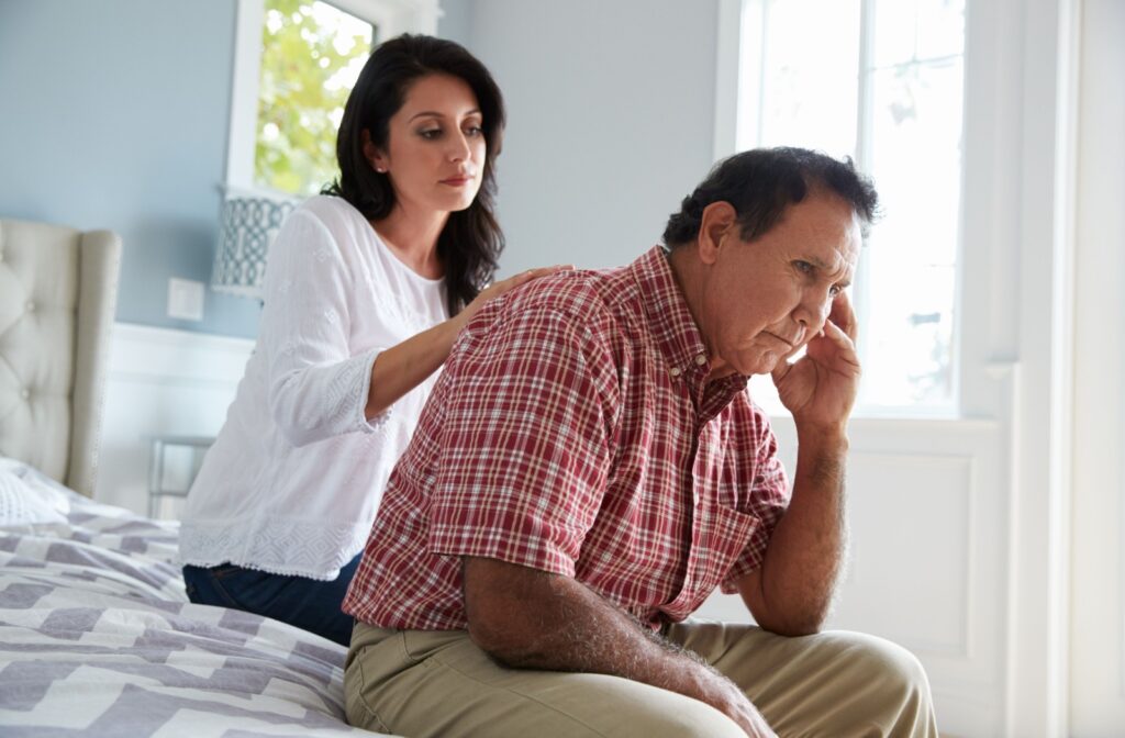 An adult rubs their older parent’s back to comfort them through frustration with the changes dementia is causing