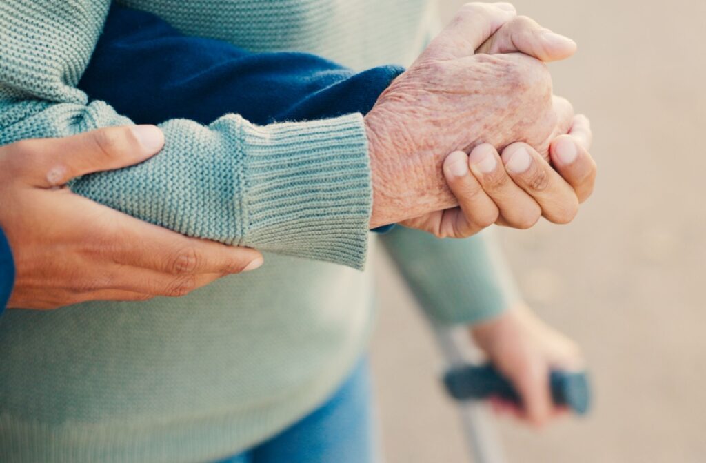 Someone helps an older adult in assisted living with getting around.